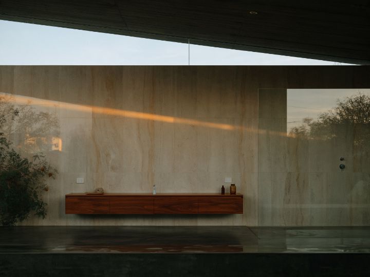 A bathroom lit from a high window under the roof, concrete and pale stone