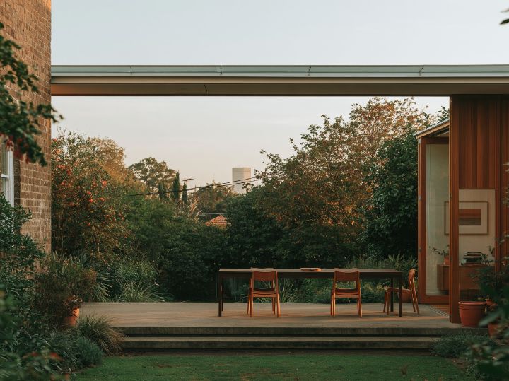 Where the old house meets the new wing: a step down, a band of glass, the dining table in the sun