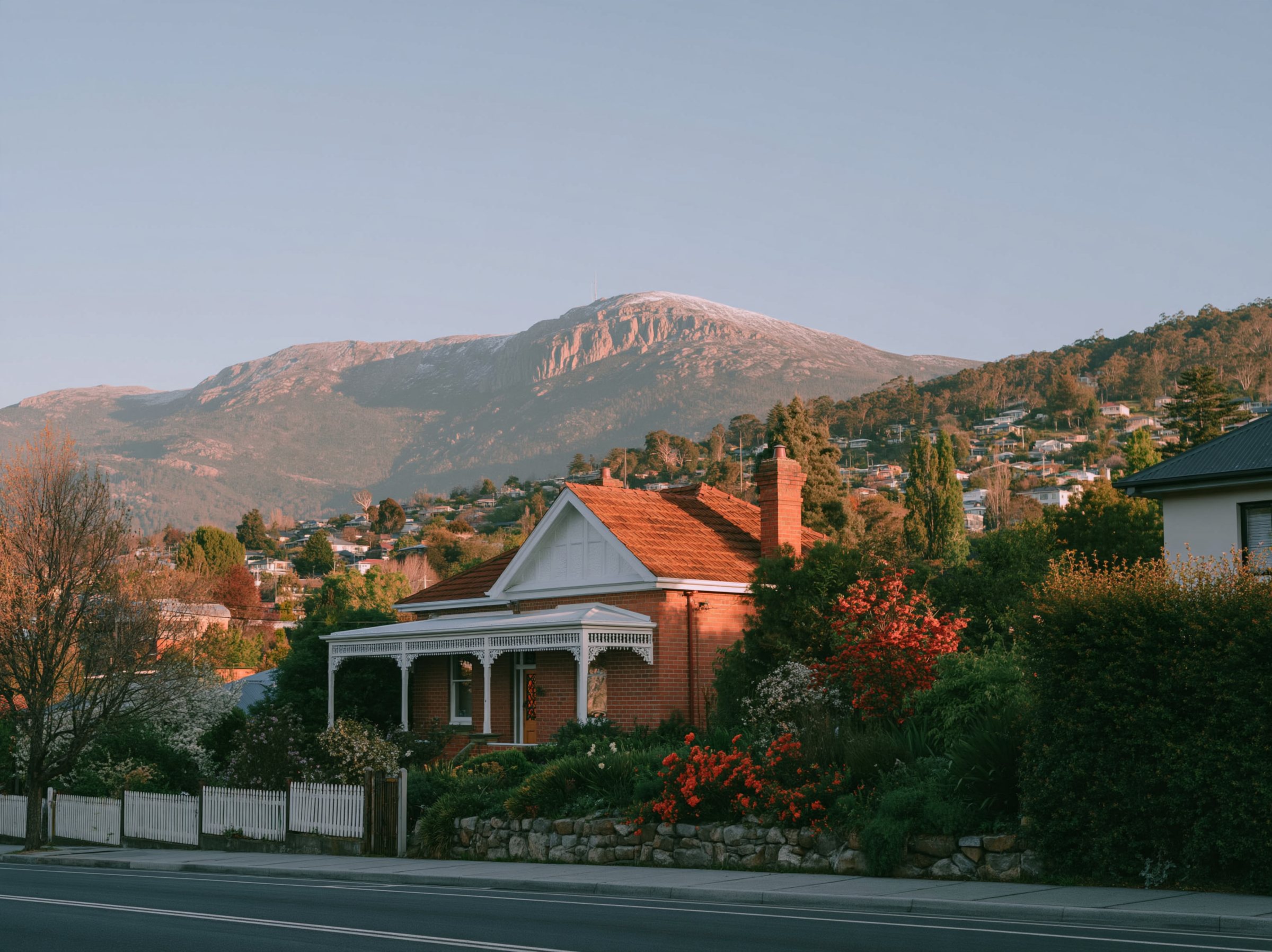 Red brick and a dutch gable, a timber verandah with fretwork, the hill rising behind