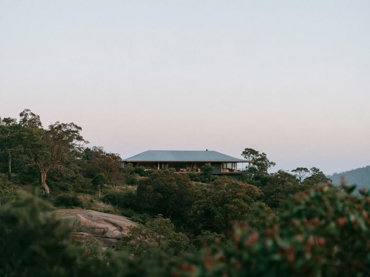 A steel gable on a steep block, the house stepping down the hill in two levels