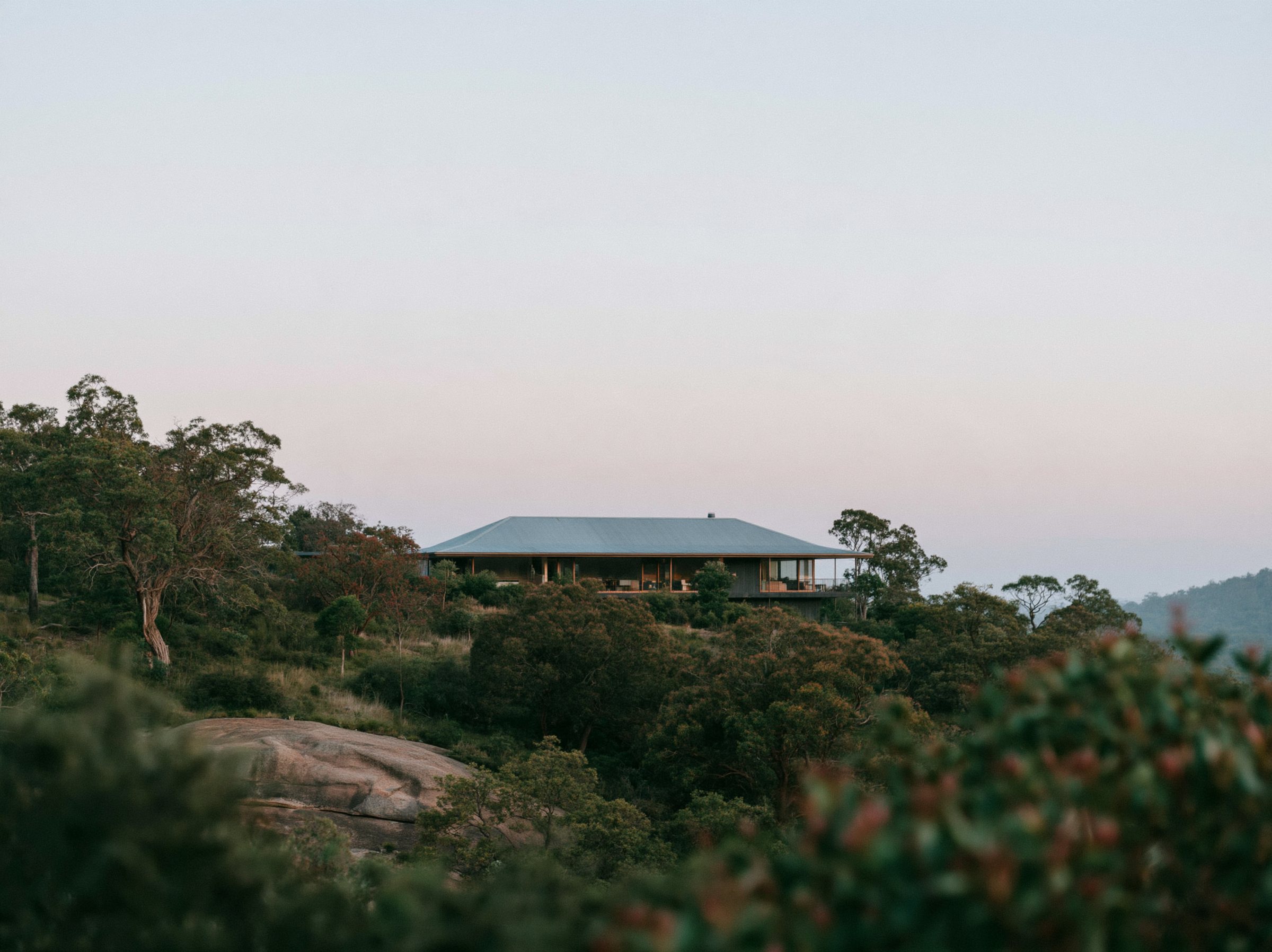 A steel gable on a steep block, the house stepping down the hill in two levels