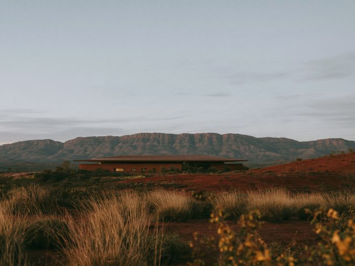 Rammed earth walls under a wide hip roof, a verandah three metres deep along the north