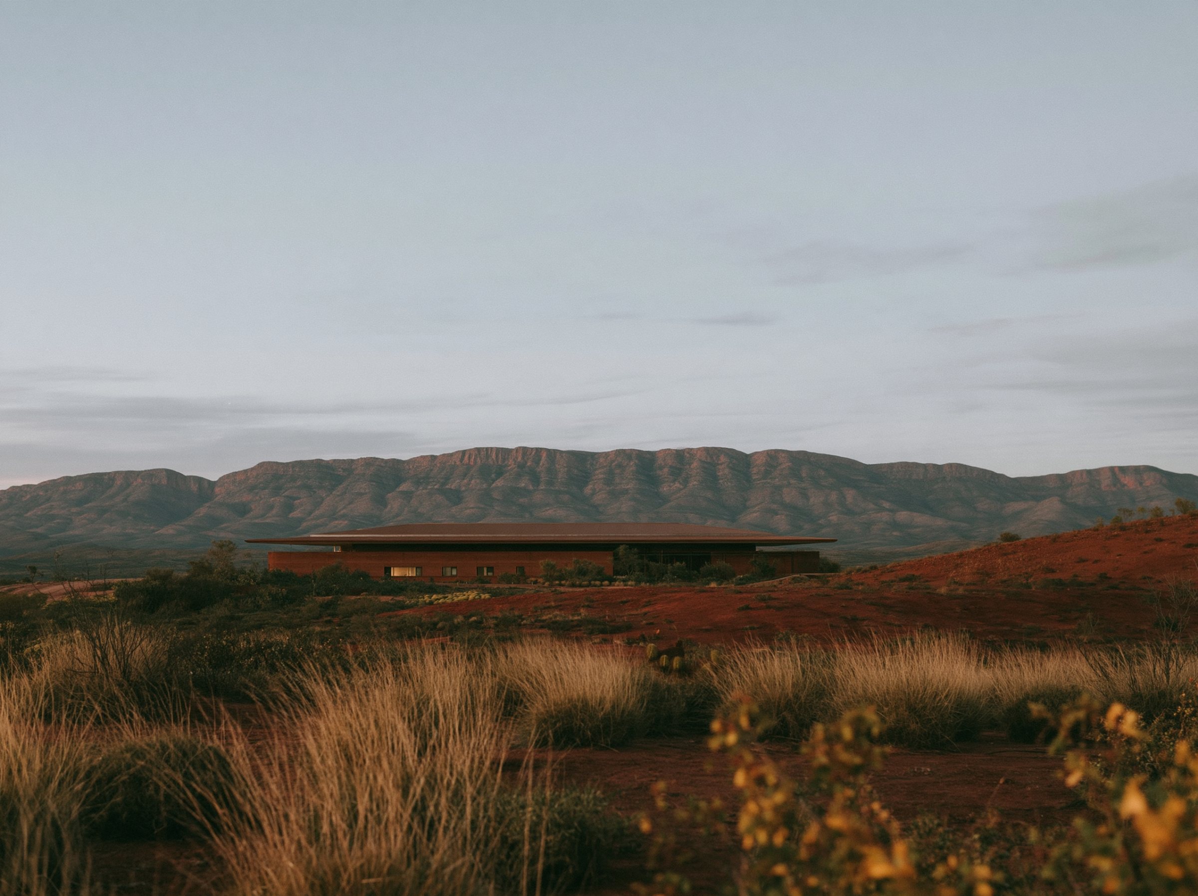 Rammed earth walls under a wide hip roof, a verandah three metres deep along the north